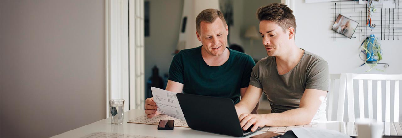 To menn sitter med pc-en og ser på en regning