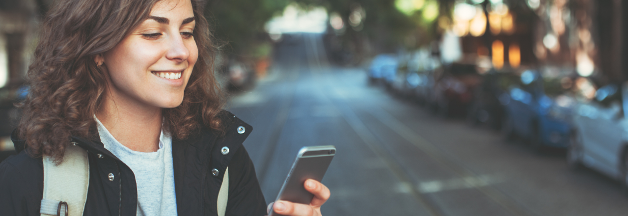 Kvinne sjekker mobilen i en bygate