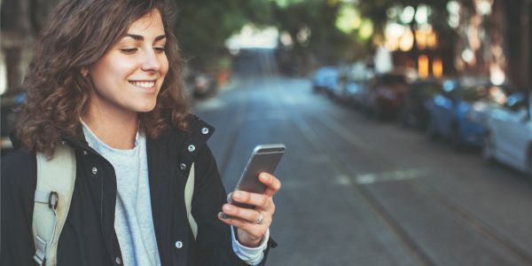 Kvinne sjekker mobilen i en bygate