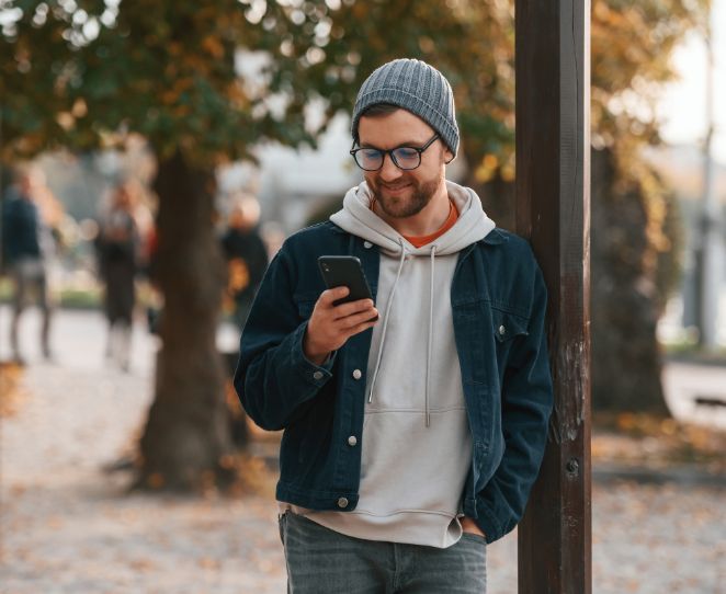 Mann bruker mobilen i en park